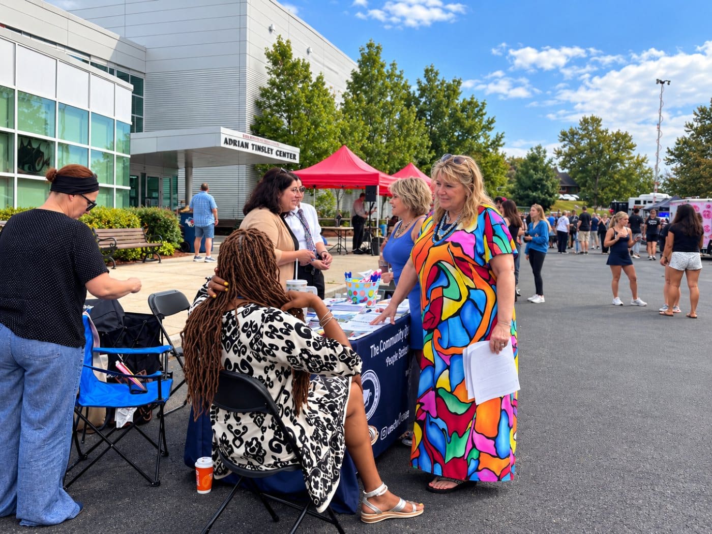 Kim Krawczyk and Susie Lordi talking with community members at a table outside the Adrian Tinsley Center